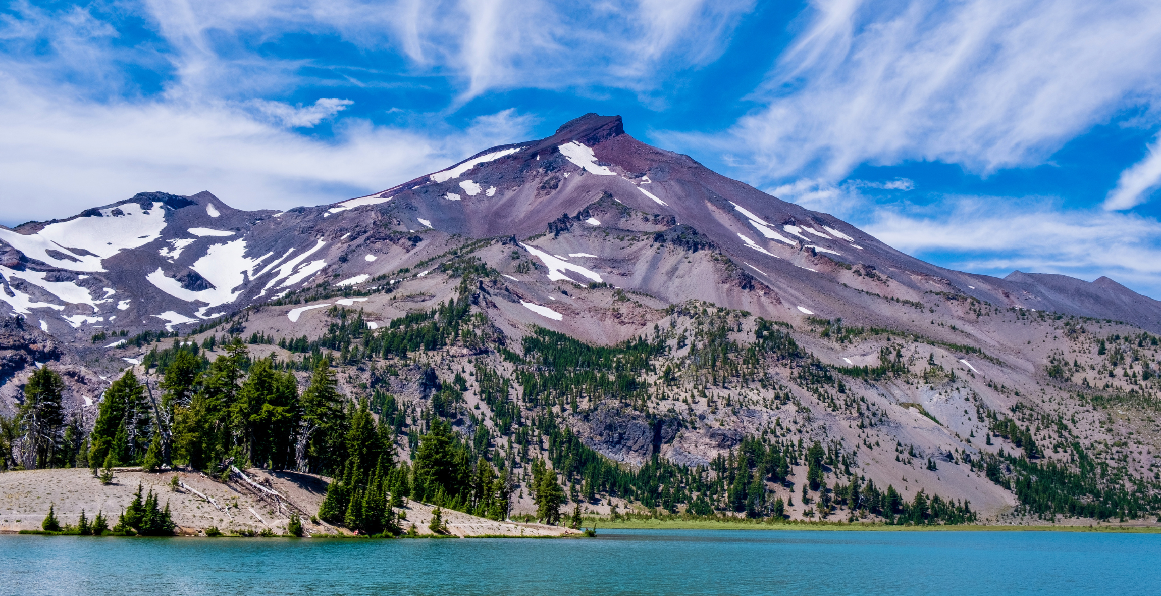 A snowy mountain sits behind a blue lake in Oregon