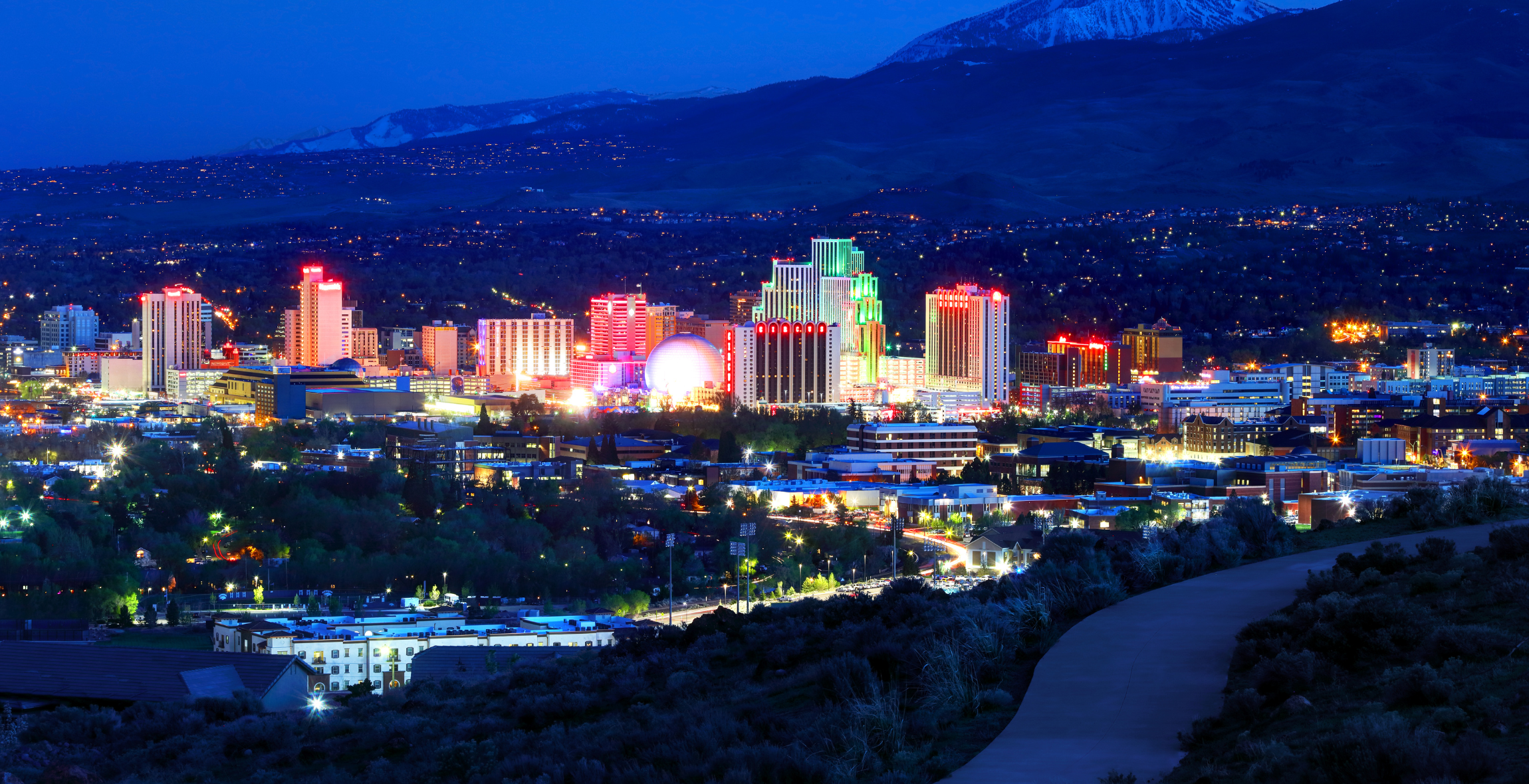 Mountains in the background of a lit up colorful city