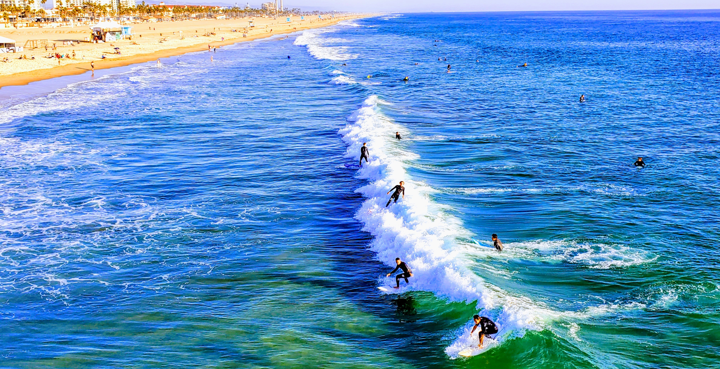 Multiple surfers ride a wave in the ocean in Huntington Beach California