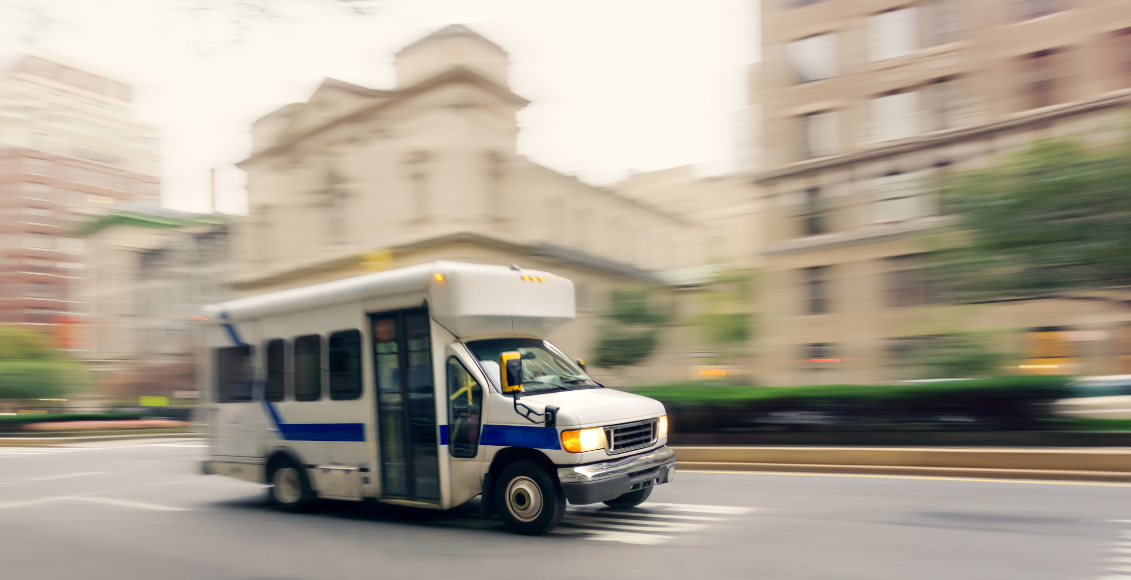 White shuttle bus drives down the road