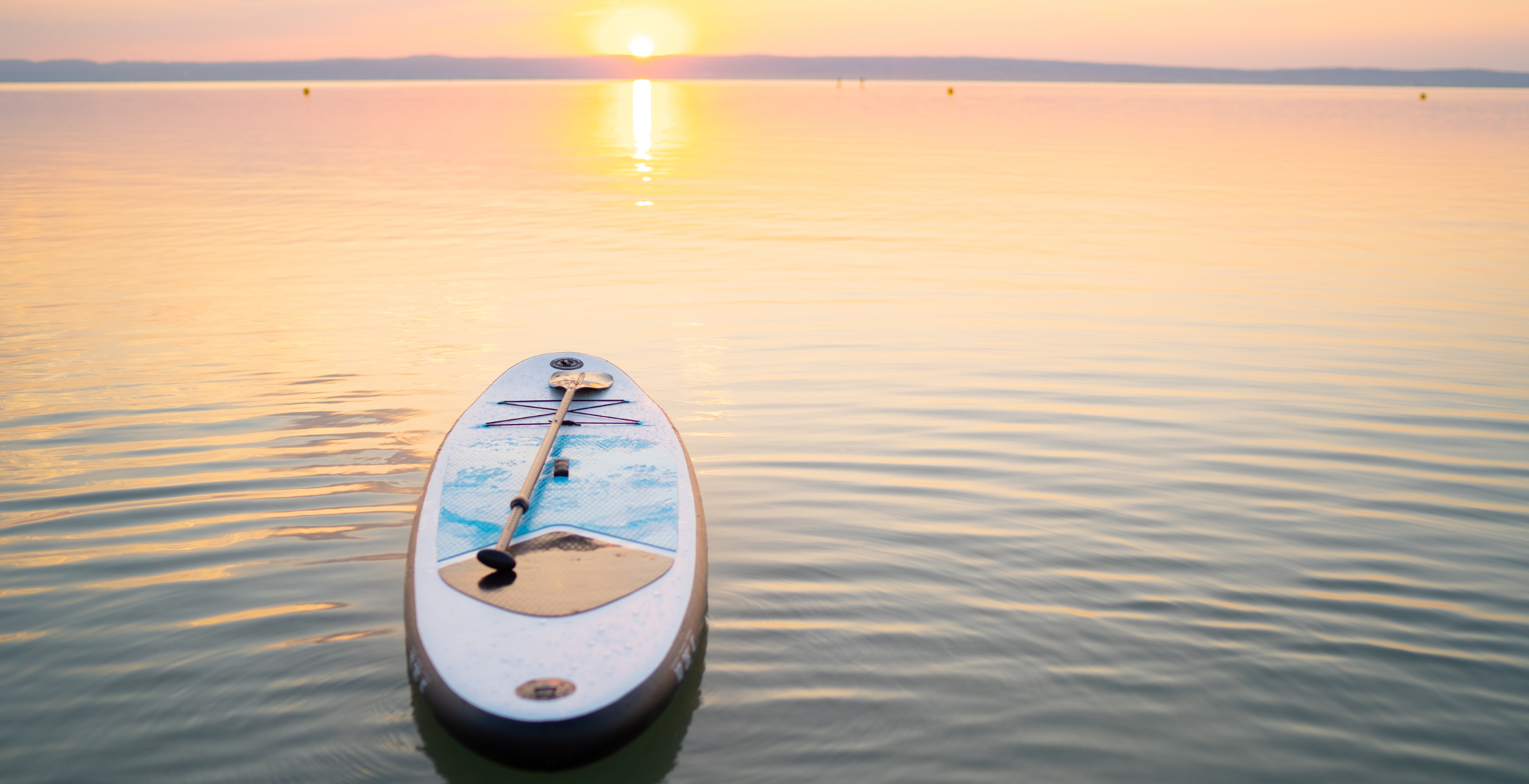 a paddle board sits in the water during sunset in California